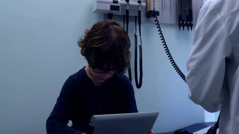 vista frontal de un lindo niño caucásico usando una tableta digital en una clínica moderna 4k
