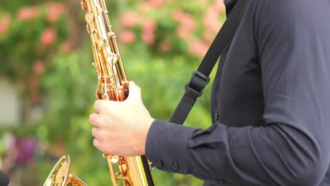 manos de hombres tocando el saxofón al aire libre