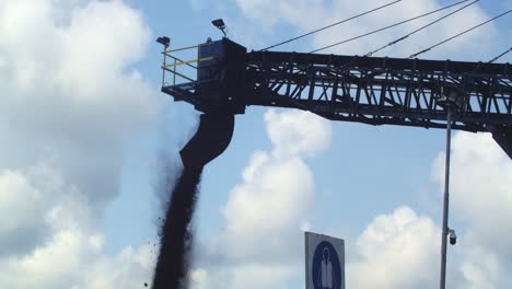 carbón cayendo del conducto de descarga de la cinta transportadora contra el cielo