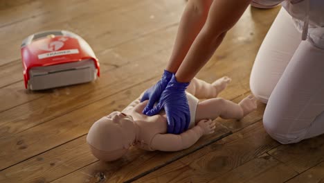 Close-up-shooting:-A-professional-nurse-in-a-white-medical-uniform-teaches-a-group-of-people-first-aid-and-demonstrates-cardiopulmonary-resuscitation-techniques-using-a-baby-dummy.-Medical-training-session