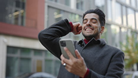 man celebrating with phone in city