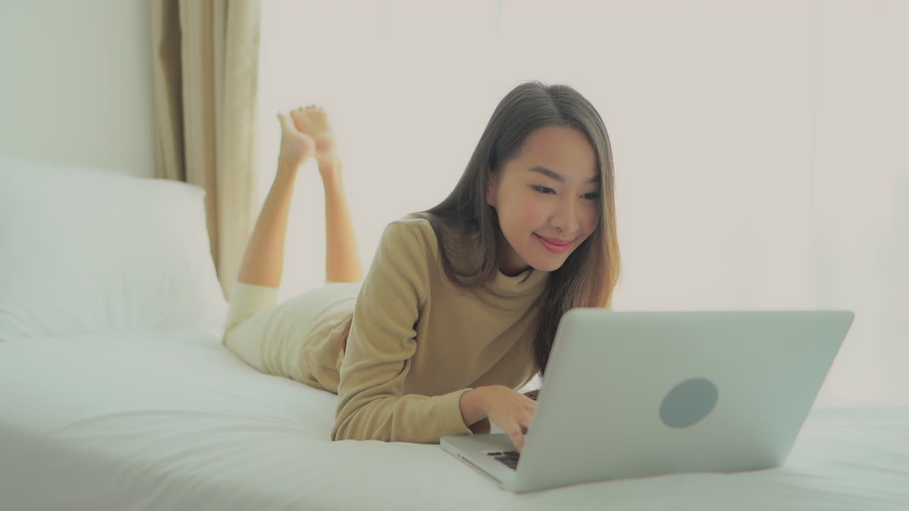 Lying on a hotel bed this digital nomad gets work done no matter where she is