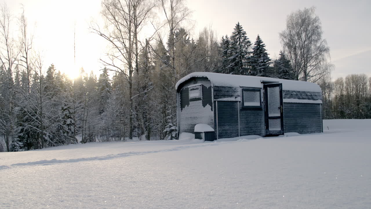 Una donna vestita caldamente che esce da una baita in un paesaggio invernale innevato
