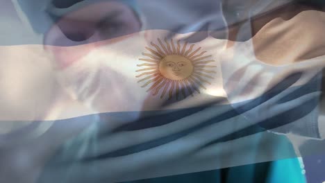 Animation-of-waving-argentina-flag-against-team-of-diverse-surgeons-performing-operation-at-hospital