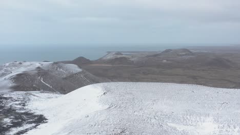 montañas cubiertas de nieve durante el invierno en islandia con vista al lejano océano atlántico, antena