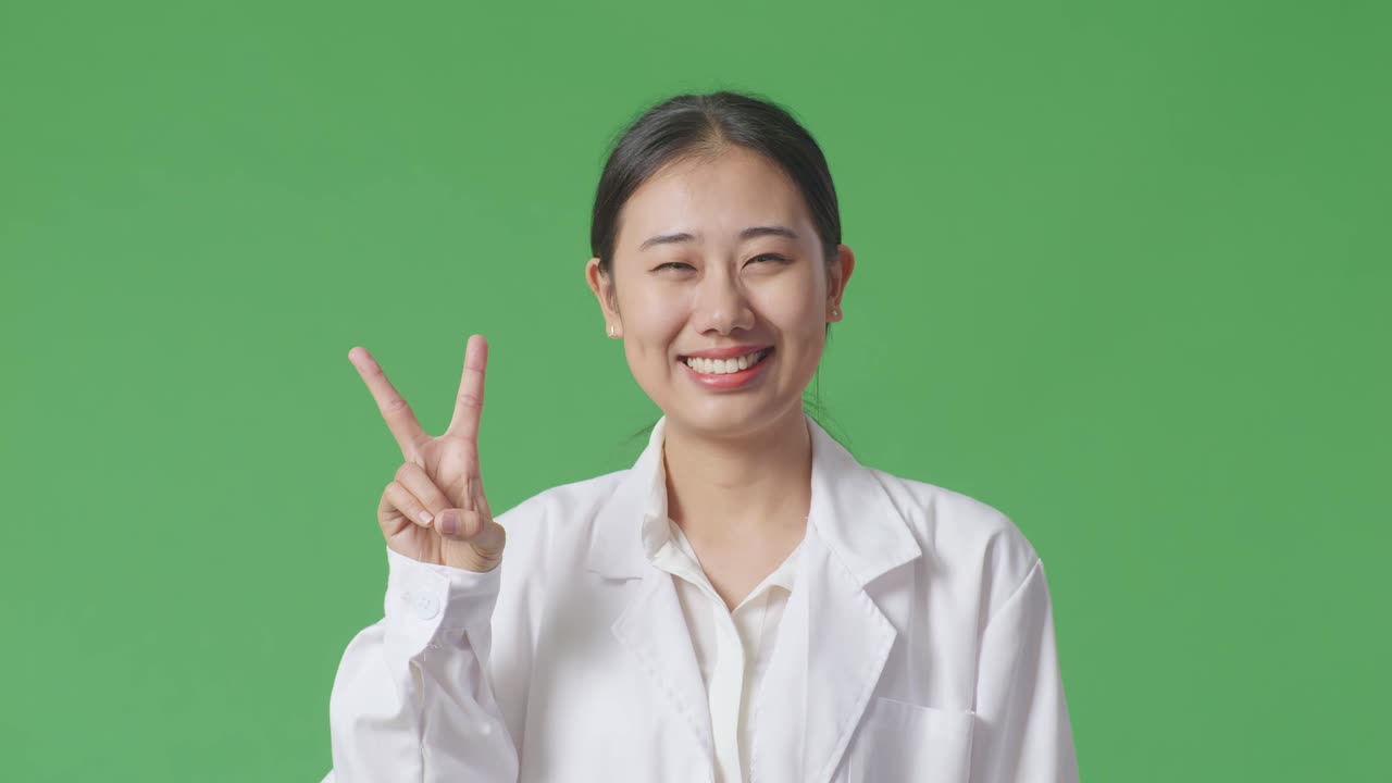 평화 표지판 을 보여주는 실험실 코트 를 입은 미소 짓는 여자