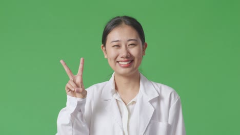 smiling woman in lab coat showing peace sign