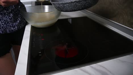 female hands pouring pancake mixed in a frying pan. homemade food. slow motion shot