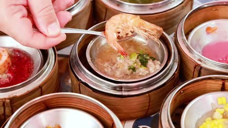 hands selecting dim sum from bamboo steamers