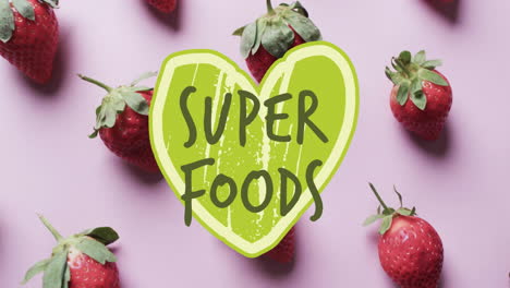 animación de texto de súper alimentos sobre fresas divididas en dos sobre un fondo rosado