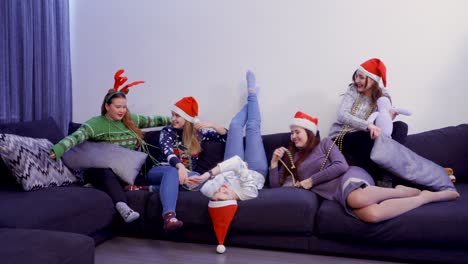 cinco chicas se divierten en el sofá en casa, en la víspera de navidad