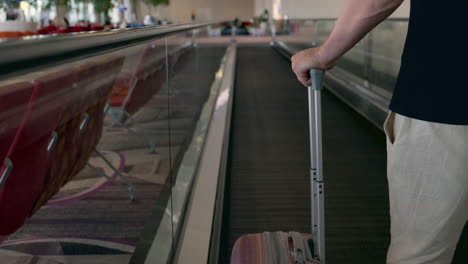 person walking on an airport moving walkway with luggage