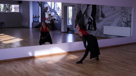 Female-dancer-stretching-in-front-of-the-mirror-before-dancing