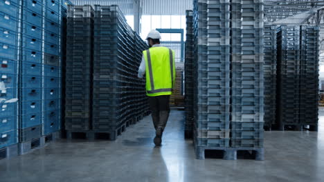 storage uniformed worker walking among shipment boxes inspecting delivery