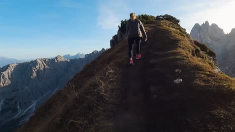 Woman-climbs-dirt-stairs-of-trail-hiking-up-ridgeline-in-Dolomites-Italy