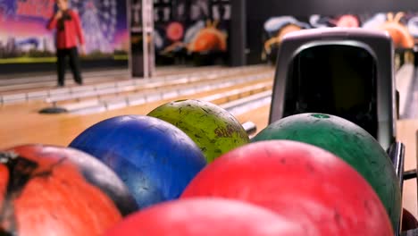 person picking up a bowling ball in a bowling alley