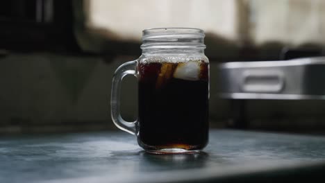 a close-up footage of pouring the iced tea over the ice cubes in a glass cup on a kitchen counter