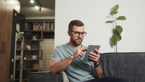 Ein-Gutaussehender-Mann-Mit-Brille-Durchsucht-Das-Internet-über-Ein-Tablet