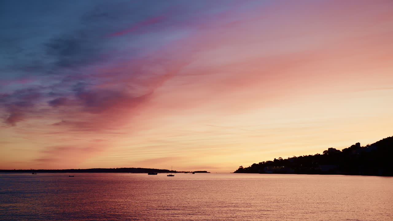 Beautiful sunset sky in warm shades of orange, pink, and purple above a calm coastline in the French Riviera