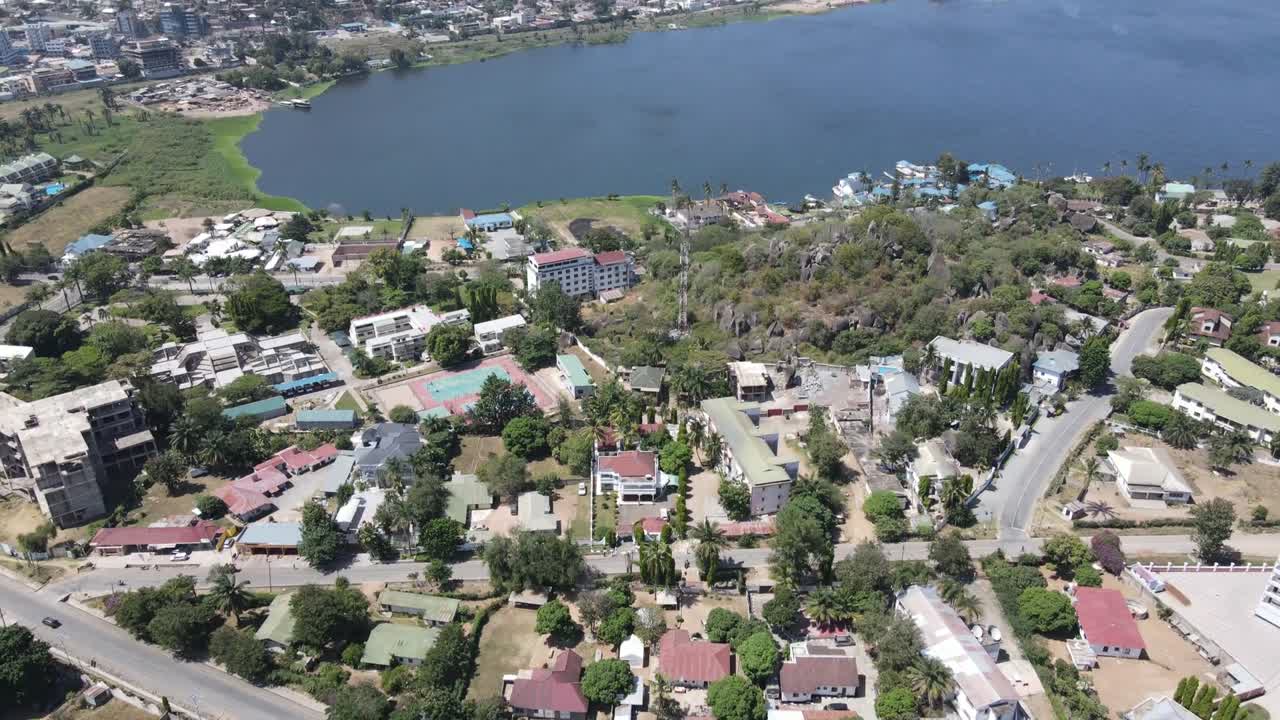 A drone tilt-up shot transitions from suburban houses to the expansive view of Lake Victoria in Africa. Captures the harmony between urban living and the breathtaking beauty of the lake.