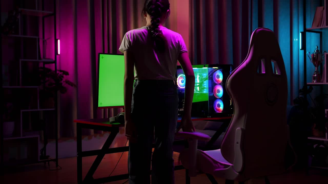 una adolescente asiática sentada jugando a un videojuego en una computadora con una pantalla verde simulada