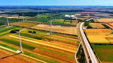 green, yellow and brown patches of fields in the picturesque countryside. wind turbines stand still on a windless day. aerial view