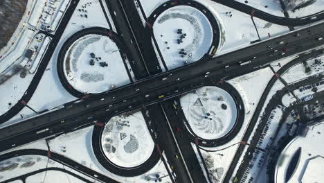 tráfico de vehículos en la intersección de la autopista en invierno. vista superior cruce de carreteras nevado
