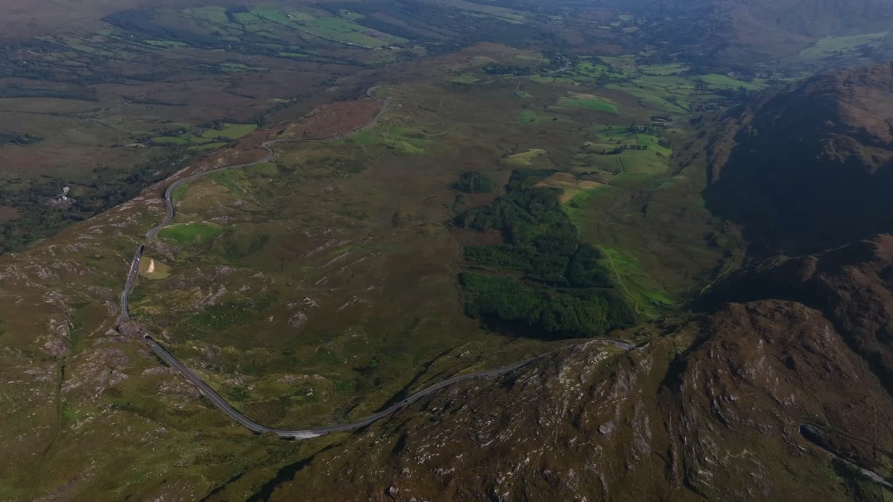 Caha Pass, County Cork, Ireland, September 2024. Drone pushes forward in a high angle panoramic overview of the winding road passing through the rugged mountain landscape on border with County Kerry.
