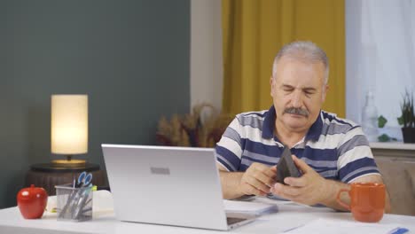 Home-office-worker-old-man-showing-his-empty-wallet-to-the-camera.