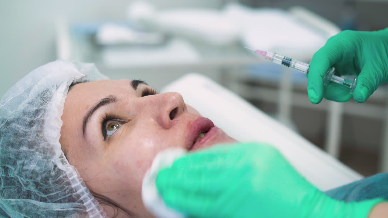 el cosmetólogo hace una inyección para el aumento de los labios a la mujer