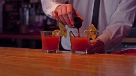 bartender pouring cocktail into glass at bar counter in bar