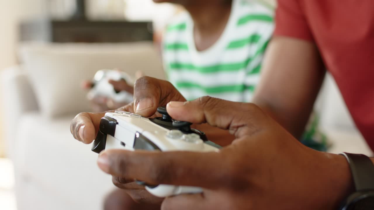 Mani appoggiate sui controller che premono i grilletti, amici che si sporgono durante il gioco su un divano beige