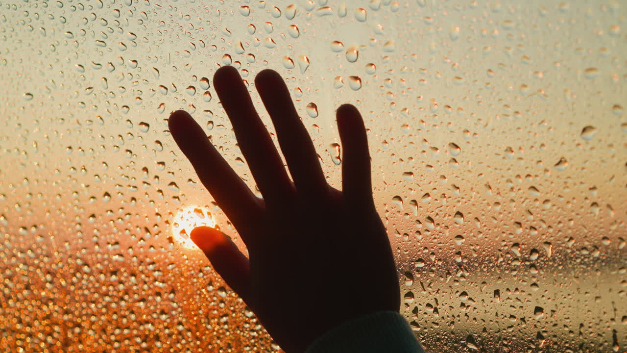 은 창문에서 슬의 상징으로 손바닥 실루 클로즈업 유리 위에 검은 손과 은 방울