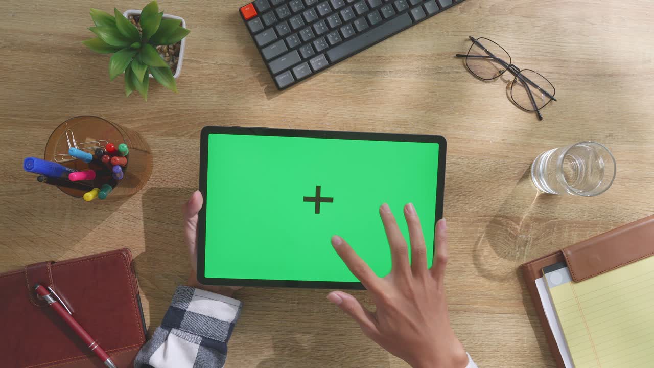 persona usando una tableta con una pantalla verde en un escritorio de madera