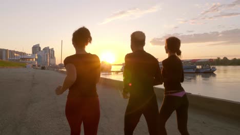 group of people running at sunrise along a riverside