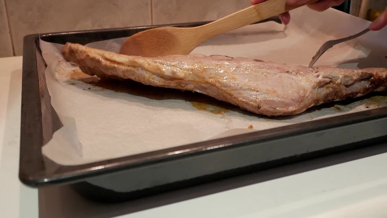 Preparing a rack of ribs, hand cutting with a fork to tenderize it before cooking