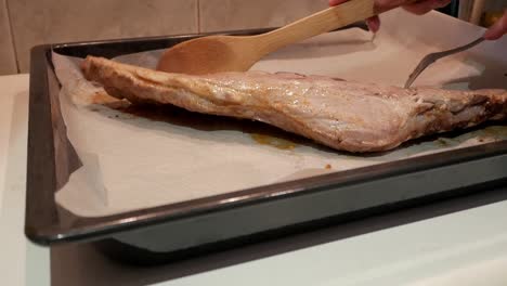 preparing a rack of ribs, hand cutting with a fork to tenderize it before cooking