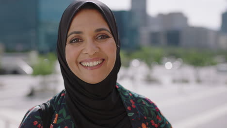 close up portrait of beautiful mature muslim woman smiling friendly at camera in sunny urban city wearing traditional headscarf