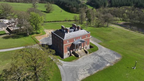 bellamont house, county cavan, ireland, april 2023. drone pullback from historic red-brick mansion, estate grounds and scenic countryside aerial view on sunny day.