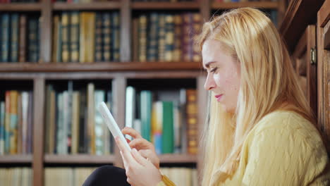 una mujer usa una tableta en la biblioteca de su casa