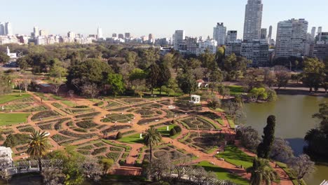 Toma-Aérea-En-órbita-Del-Hermoso-Parque-Rosedal-Con-El-Lago-Y-El-Horizonte-De-Buenos-Aires-En-Segundo-Plano