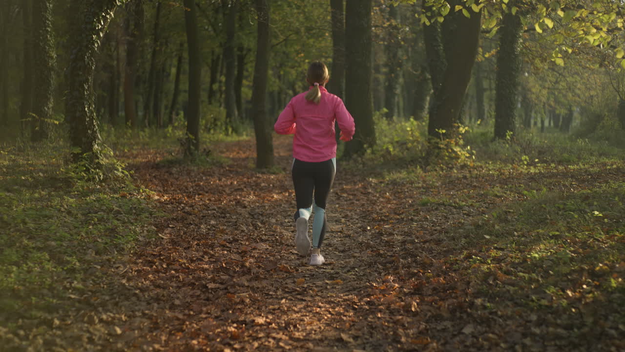 Woman Jogging on a Forest Path in Autumn