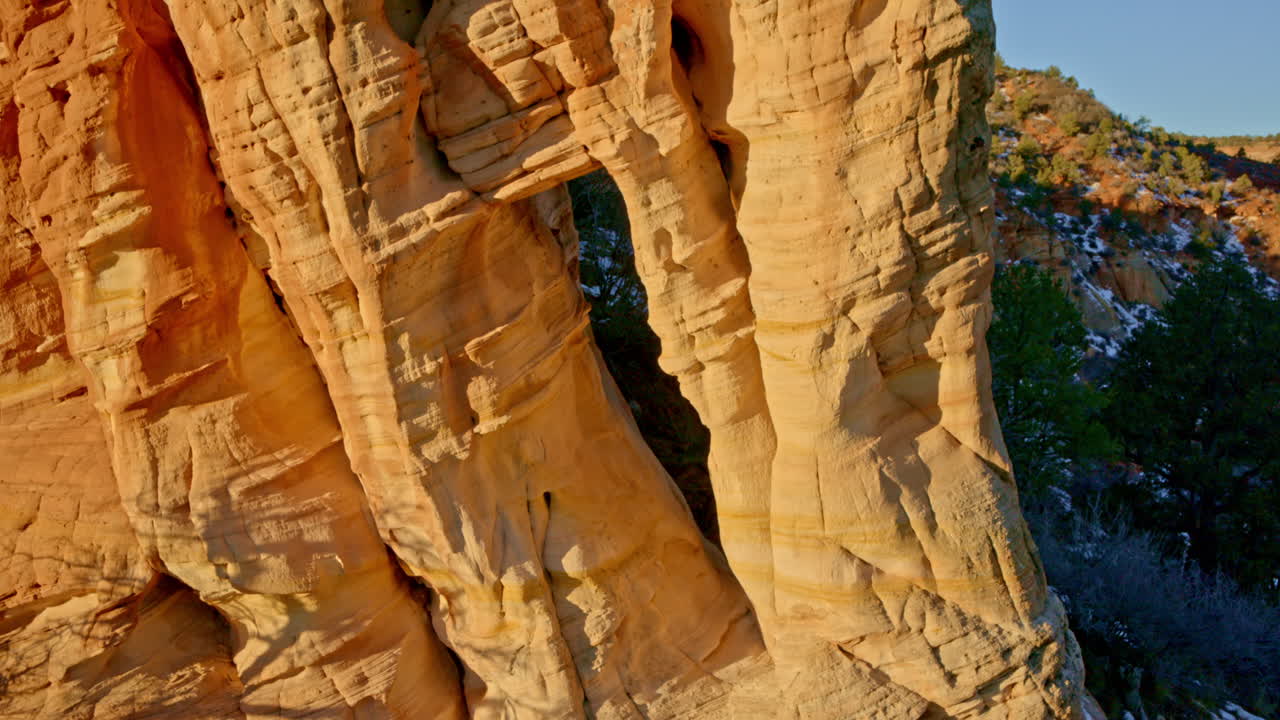 Golden sunrise light illuminates a striking natural arch in Utah’s red rock landscape, captured by drone.