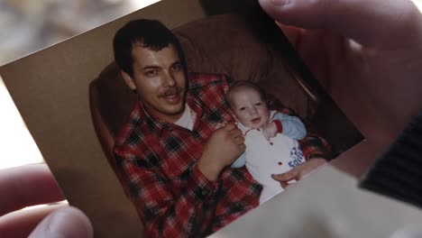 primer plano de un adolescente sosteniendo una fotografía de un padre y un hijo en cámara lenta, 60fps