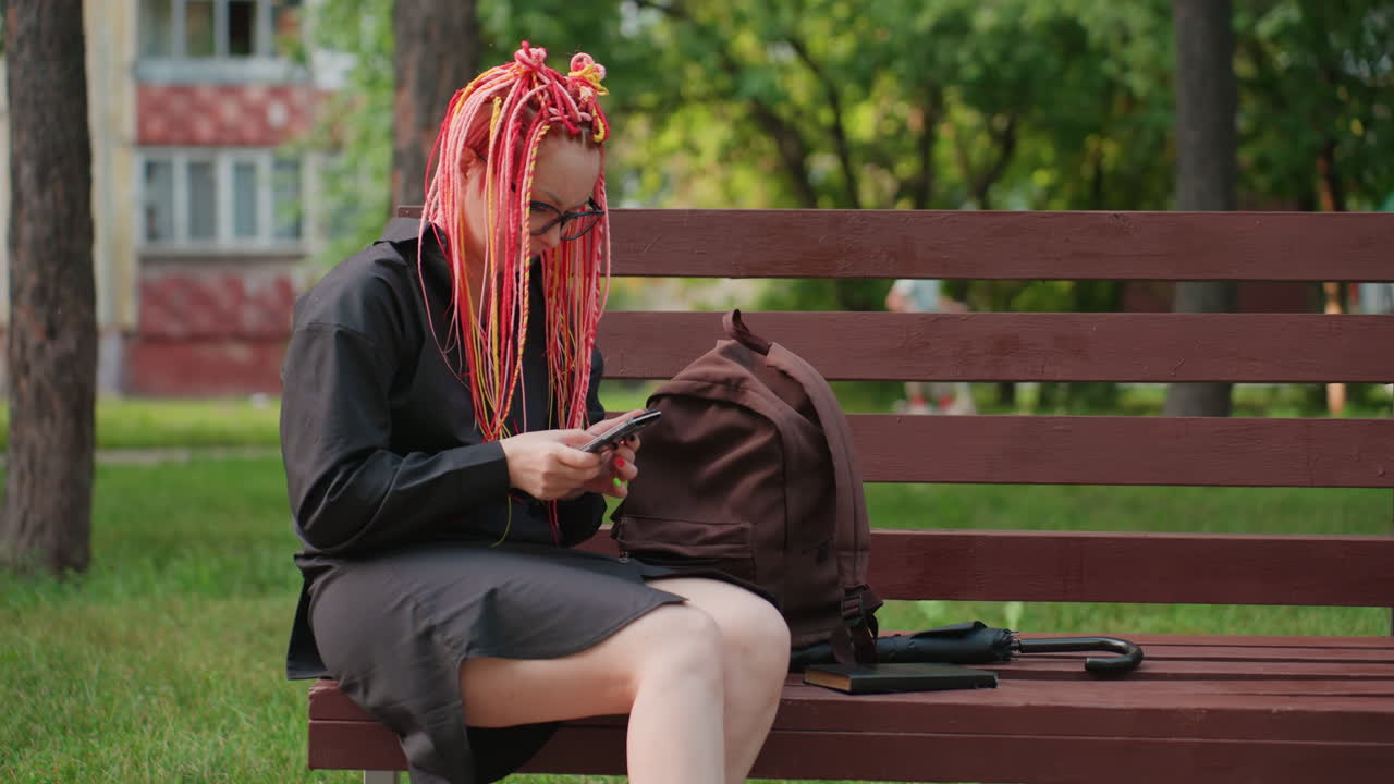 mujer discreta con un peinado colorido, mujer solitaria con un cabello vibrante disfrutando de un parque tranquilo, mujer independiente con un cabello llamativamente teñido relajándose sola en medio del entorno del parque