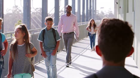 young school kids and teacher walking in school corridor