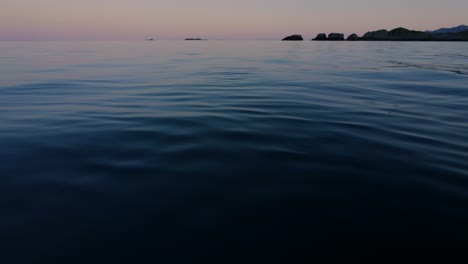 twilight at sea. beautiful summer night at calm arctic sea, with small islands and islets in the background. lofoten islands, northern norway