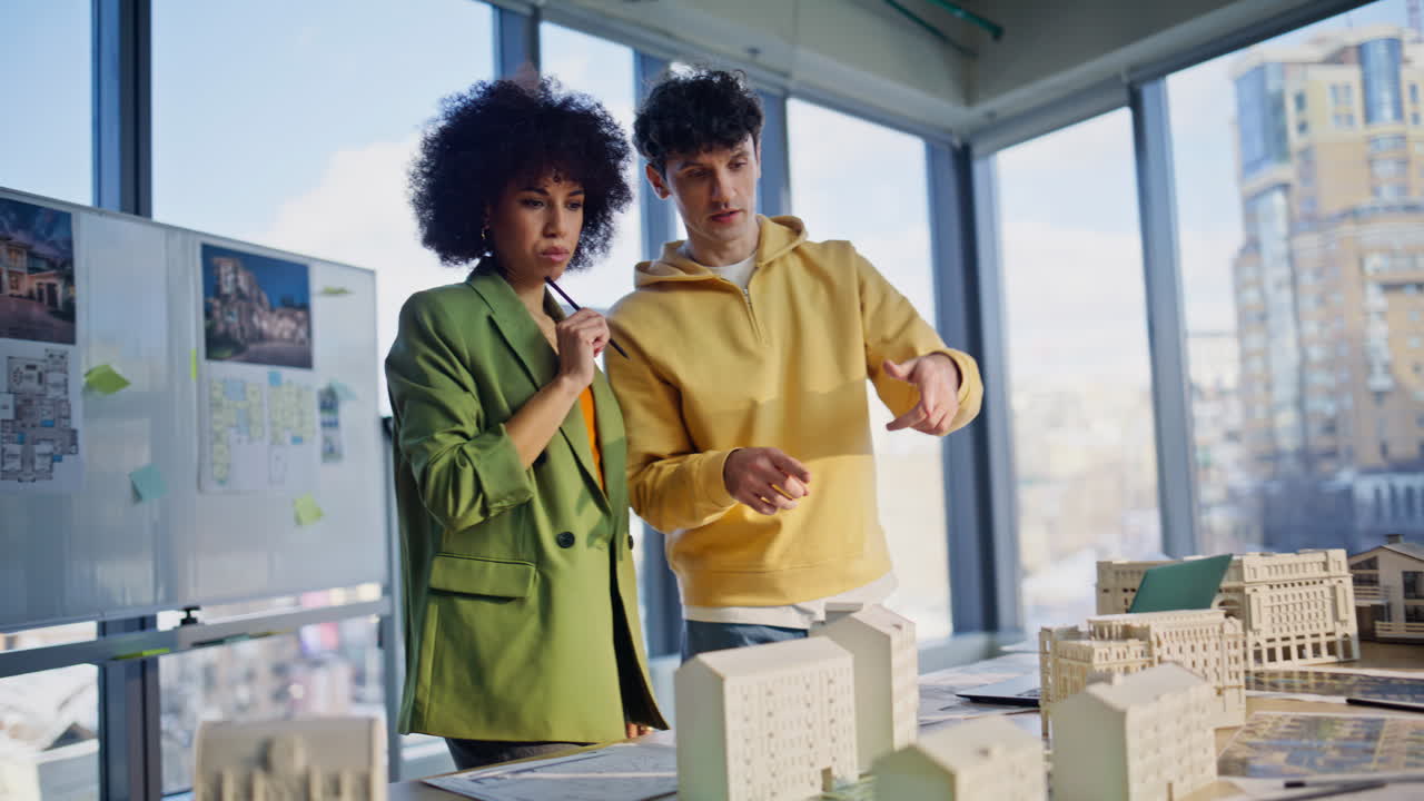 Two realtors discussing buildings models at meeting room. Smiling architects