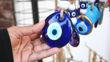 close-up of a hand holding a blue evil eye charm