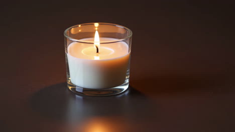 burning white candle in a glass votive